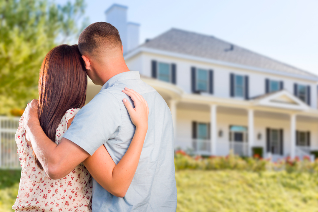 Man and woman with arms around each other looking at a new home