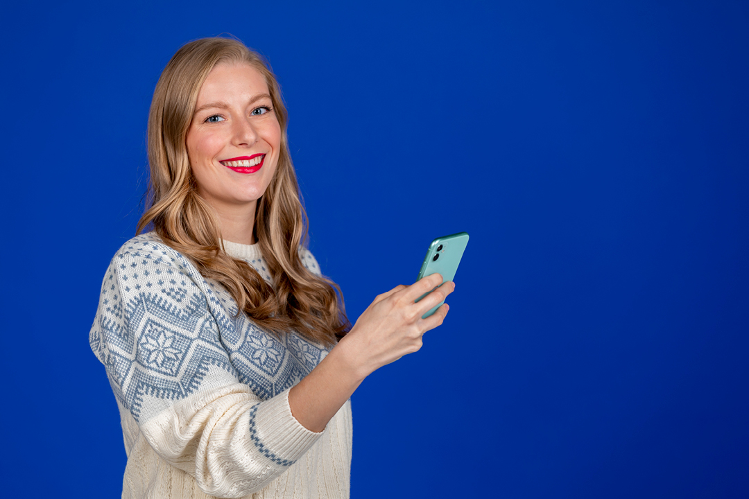 A woman holding a smartphone while looking at the camera