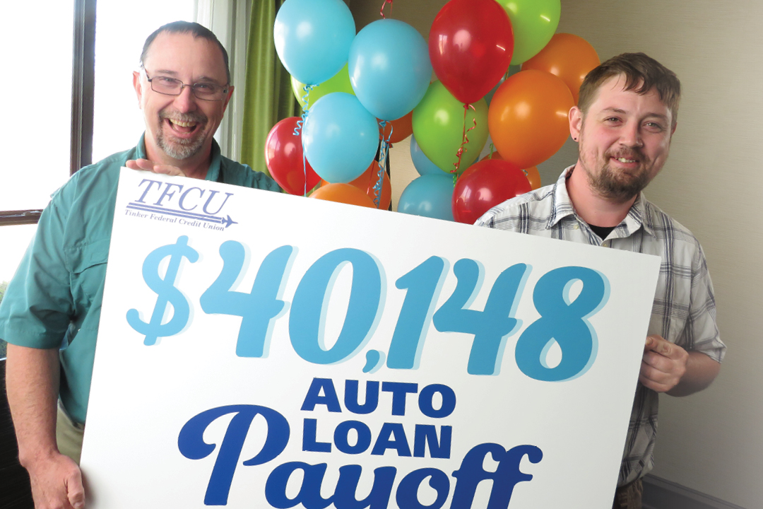 Dad and son holding an auto loan payoff sign