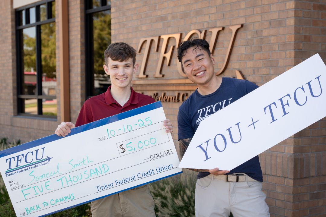 A back to campus winner holding a large check with a TFCU employee holding a sign.