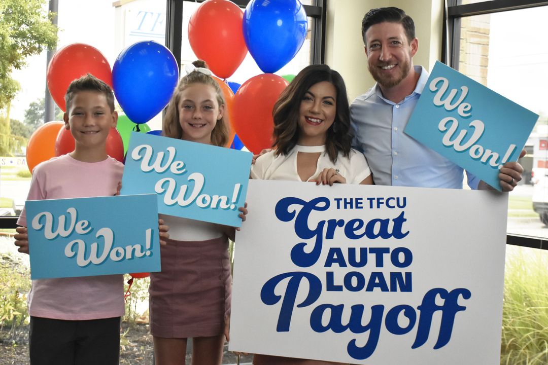 The Mars Family, winners of The 2019 TFCU Great Auto Loan Payoff, holding "We Won" signs.