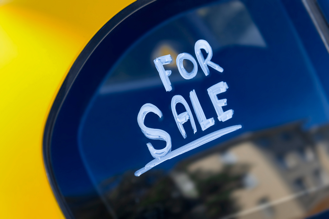 Close-up of window of yellow car with the words "For Sale" written in white.