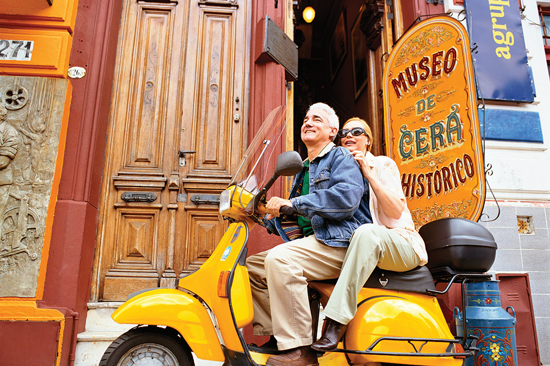 Senior man and woman riding their yellow scooter through the streets of Buenos Aires.