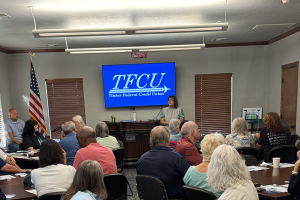 A TFCU employee teaching to a room full of older people about fraud awareness.