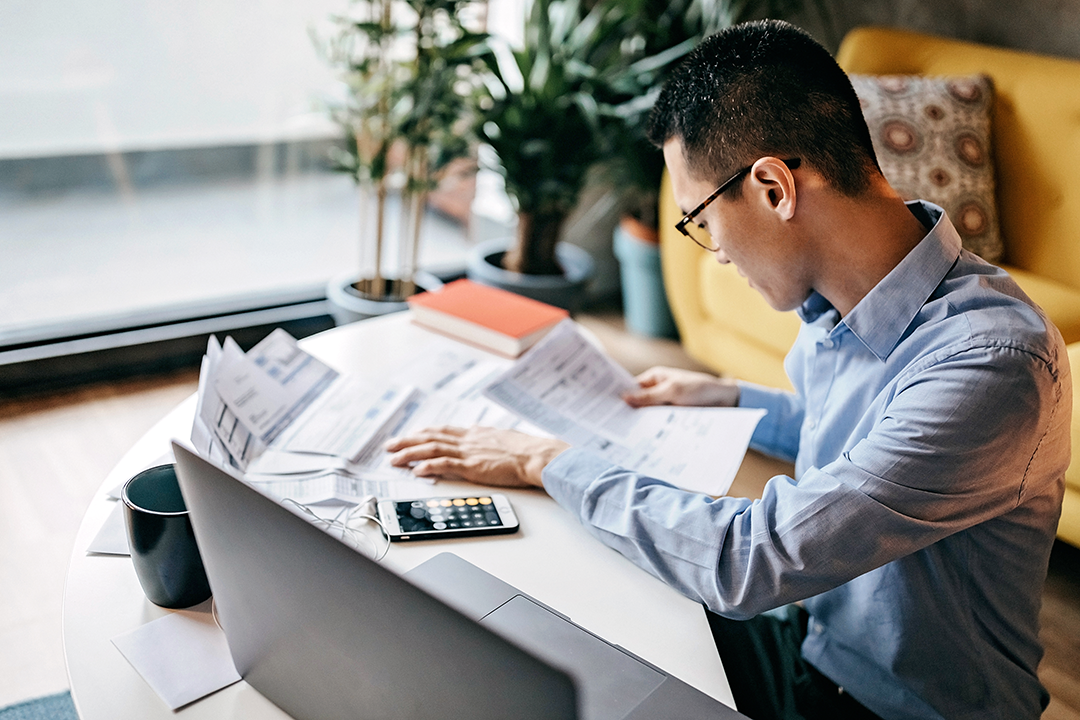 Young man sitting at his desk looking through papers