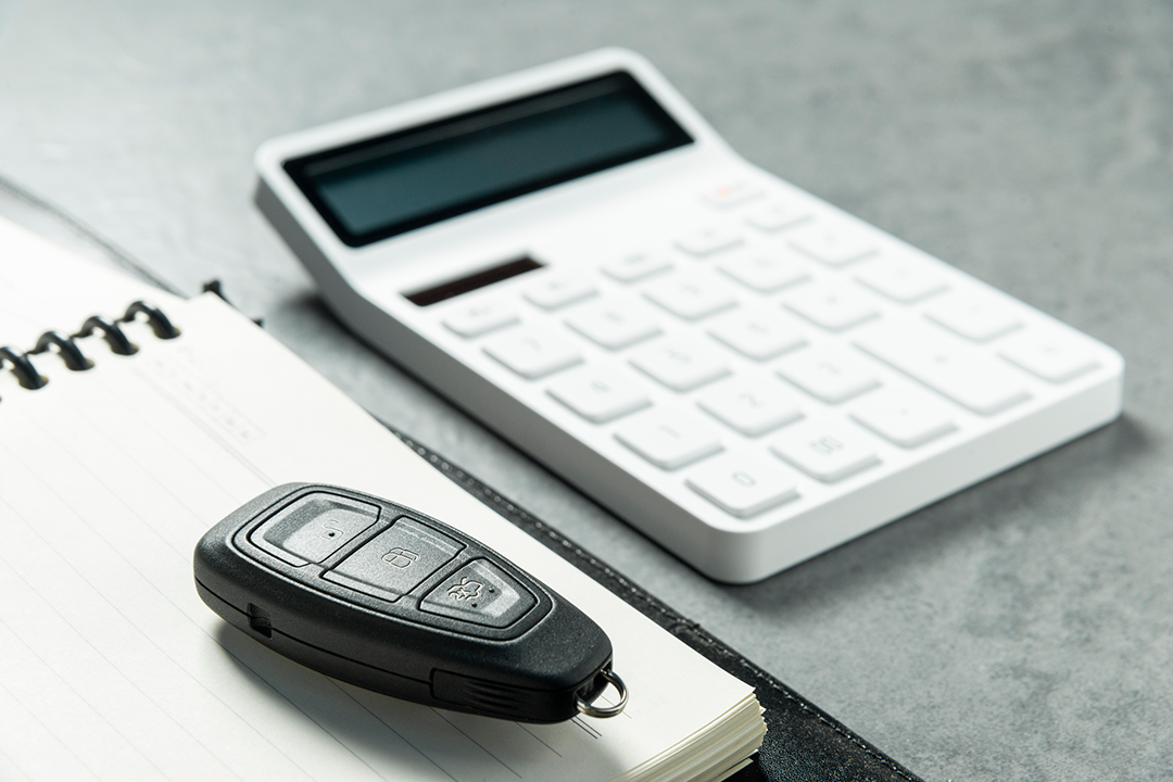 A car key fob on a notebook with a calculator.