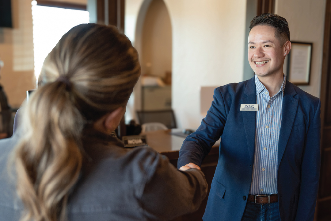 TFCU employee shacking hands with a woman.