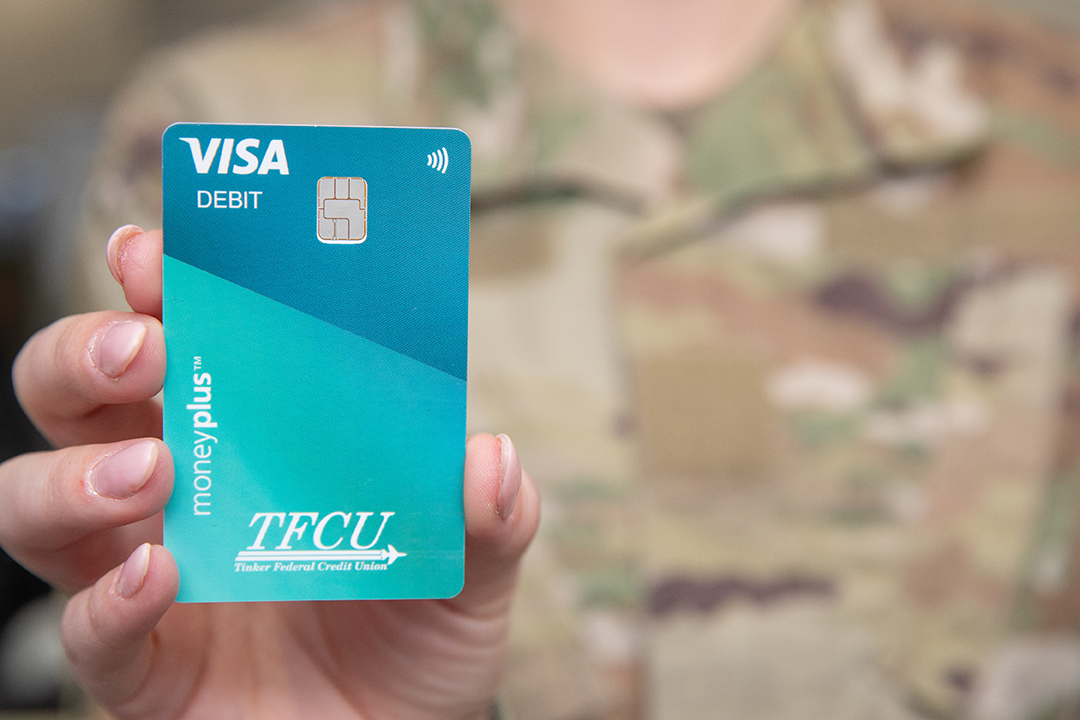 Close up of someone in military uniform holding up a moneyplus card