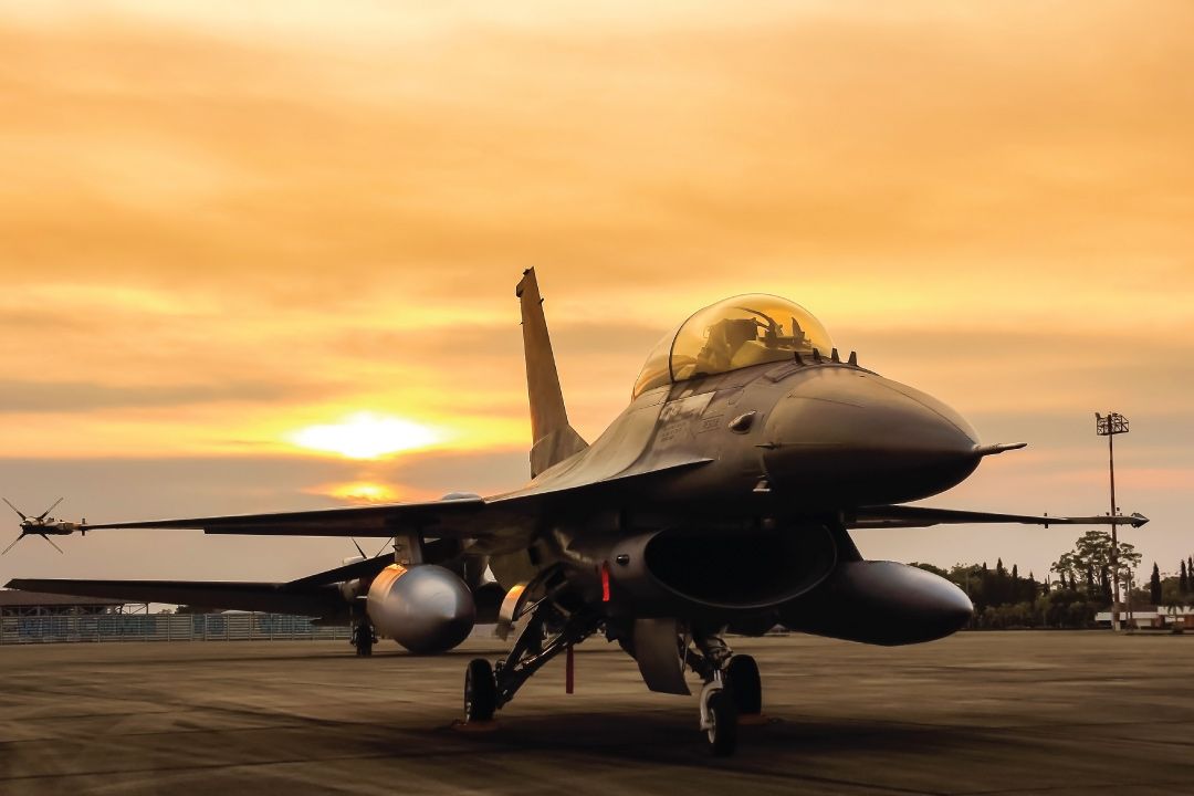 F16 Fighter jet on runway against sunset in background