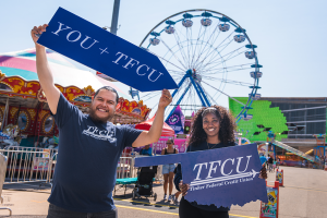 Two TFCU employees holding up signs at the oklahoma state fair.