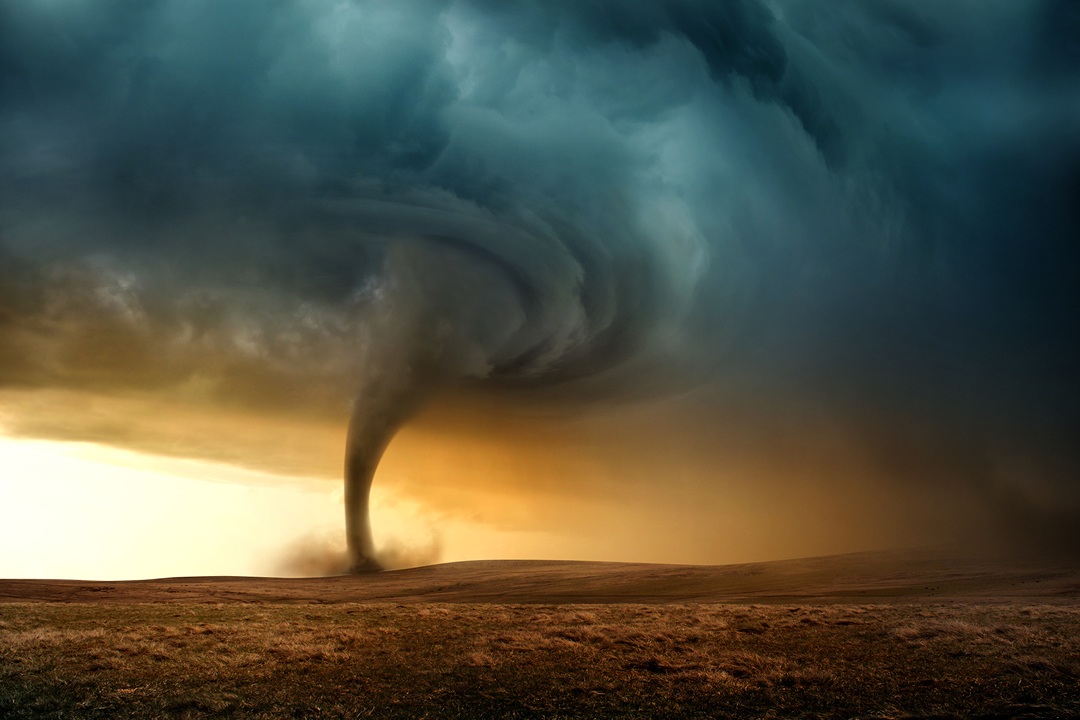 A stormy sky with a tornado going through a field