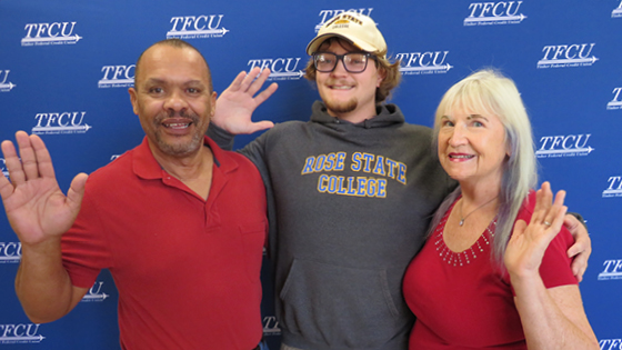 Winners of the TFCU College Cash promotion stand in front of a TFCU banner.