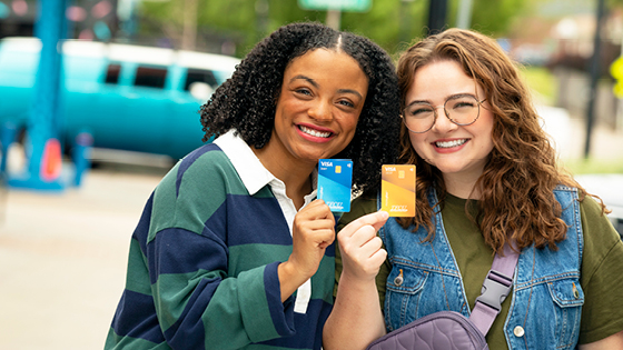 Two young teens holding up a green and yellow MoneyPlus cards.