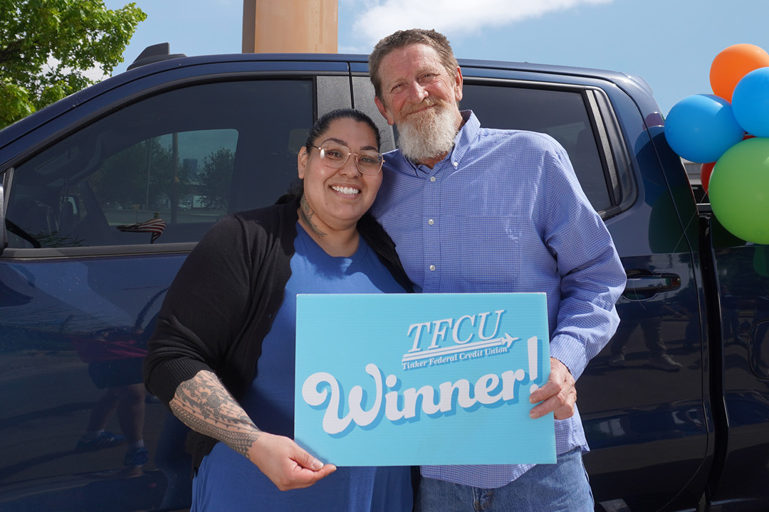 A man and a woman standing in front of a truck holding a sign that says winner.