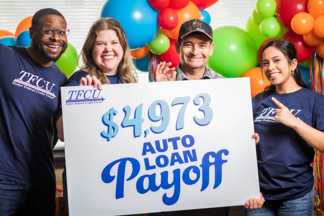 A man and three TFCU employees holding up a sign that says $4,973 auto loan payoff.
