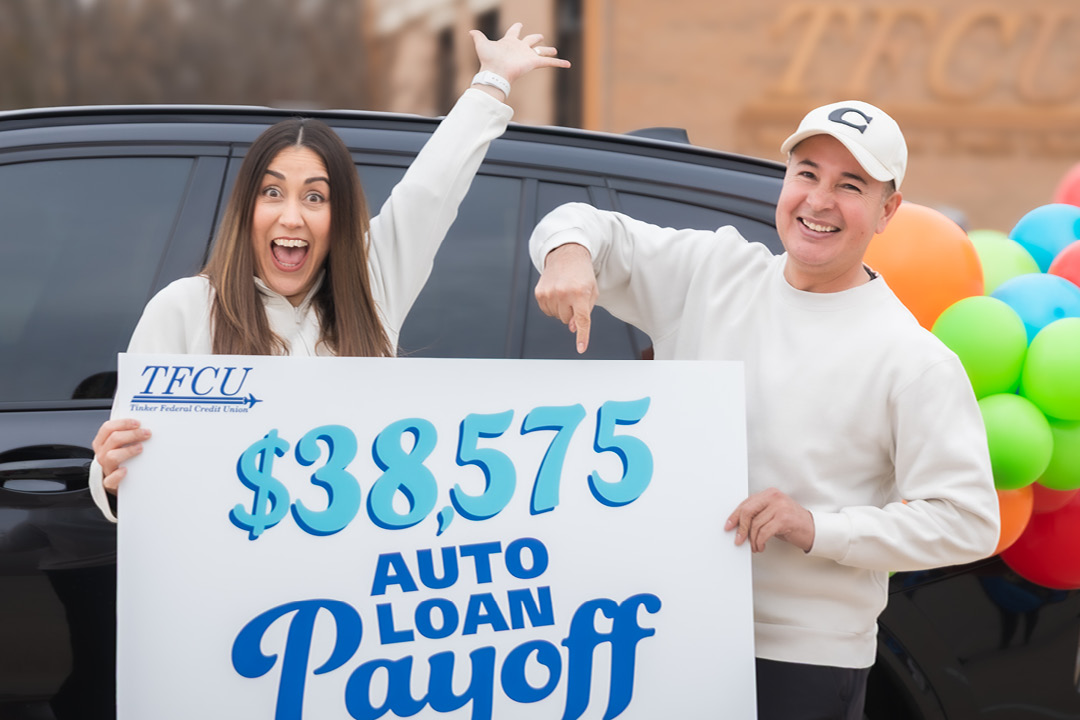 A man and woman hold up a sign that says $38,575 auto loan payoff
