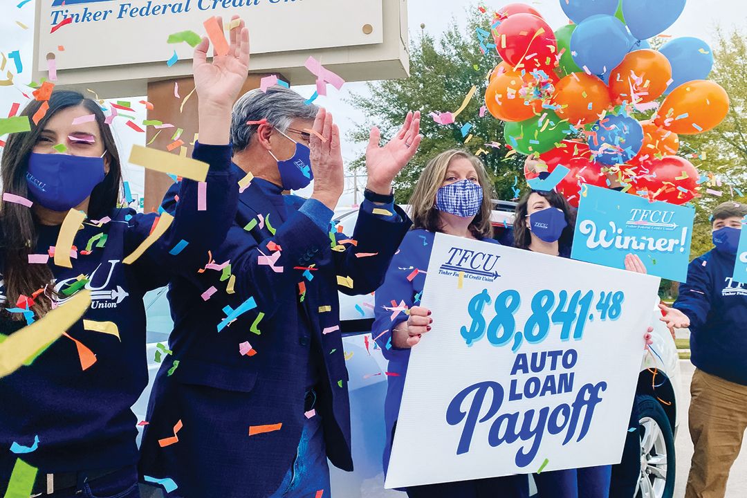 Group of people with masks celebrating with a woman holding a sign and confetti and balloons