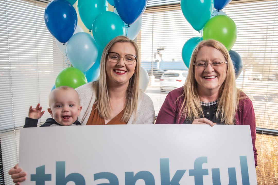 Two women and a baby with balloons in the background