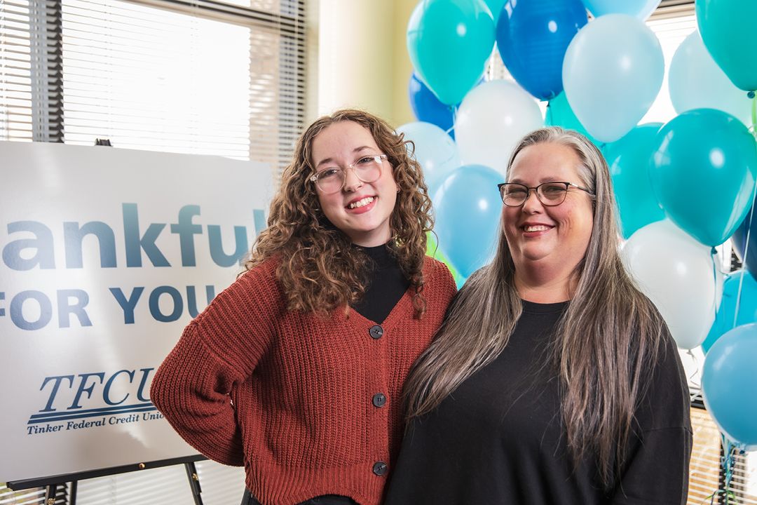 Daughter and mother standing in front of a sign and balloons