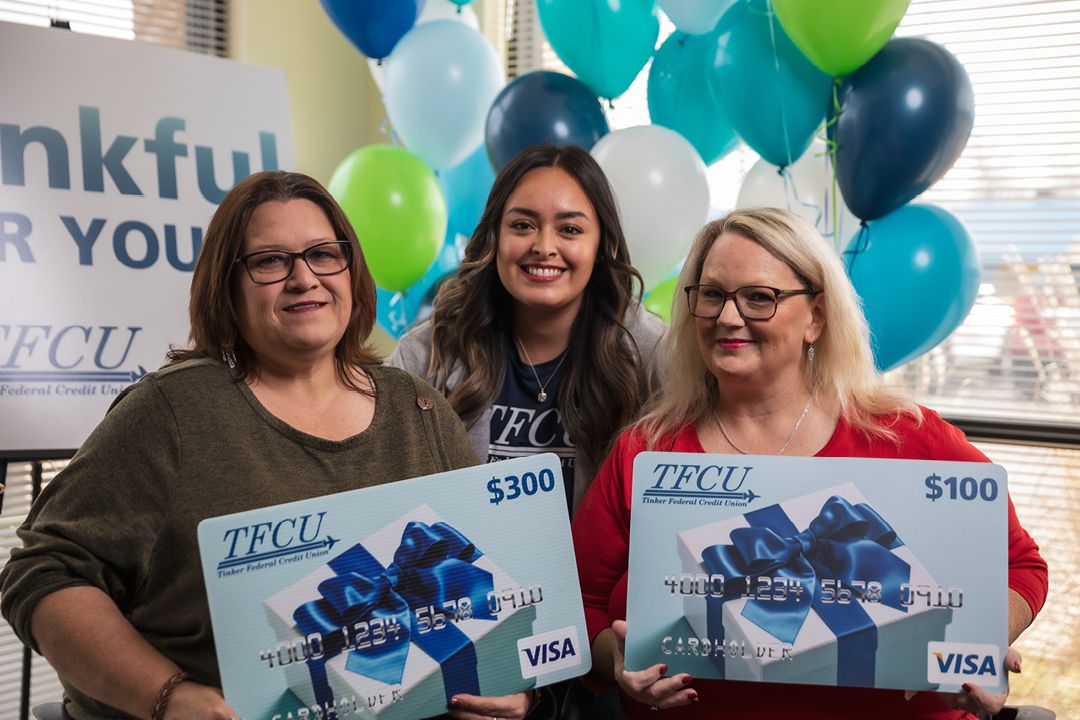 Two women holding gift card signs