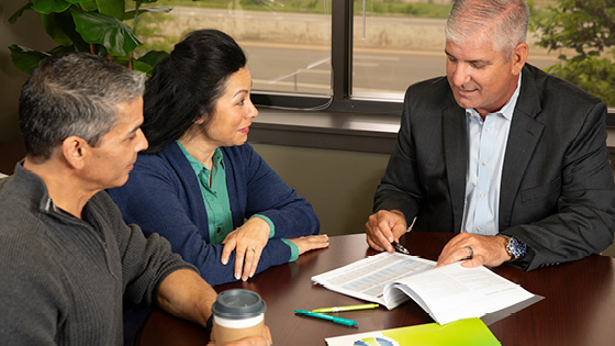 A TFCU Financial Advisor talking to a couple while looking at paperwork.