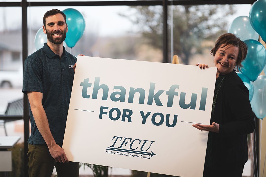 Two TFCU employees holding a sign that says "thankful for you"