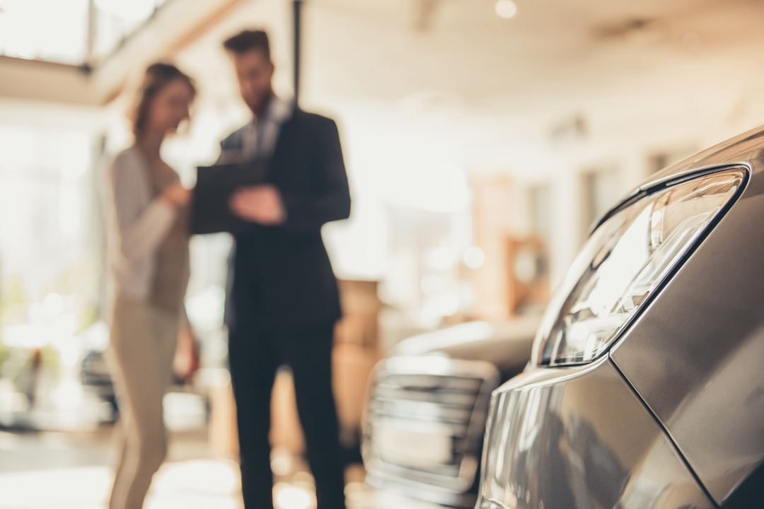 Close up view of vehicle in dealer showroom with man and woman in background